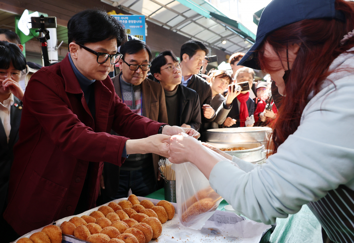 ▲한동훈 국민의힘 비상대책위원장이 15일 오전 전남 순천시 웃장을 방문해 상점에서 핫도그를 구매하고 있다.  (뉴시스)