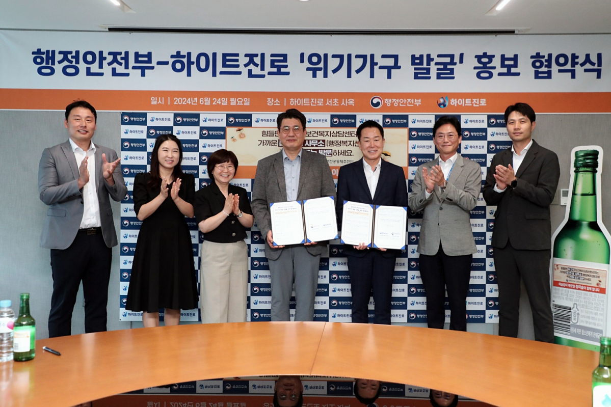 ▲하이트진로 장인섭 전무(오른쪽 세번째)와 정세영 상무(오른쪽 두번째)가 24일 오전 서울시 서초구 하이트진로 서초동사옥에서 열린 '행정안전부-하이트진로 위기가구 발굴 홍보 협약식'에 참석해 구본근 행정안전부 스마트복지안전공동체추진단장(왼쪽 네번째) 및 관계자들과 기념촬영을 하고 있다. 오는 7월부터 상담번호 등을 기재한 '위기가구 발굴' 홍보 라벨이 부착된 참이슬 소주 150만병이 유통된다. (사진제공=하이트진로)