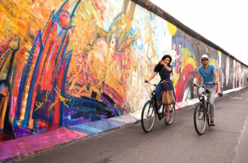 ▲베를린의 대표적인 벽화예술 지역인 이스트사이트갤러리(야외갤러리)의 벽화 앞을 자전거를 탄 커플이 지나고 있다.   사진출처 베를린관광청 공식홈페이지