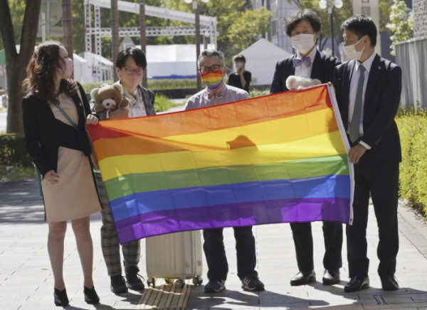 ▲2022년 10월 스즈키 젠(가운데)이 일본 시즈오카현 하마마쓰 가정법원 앞에서 법원 심리를 앞두고 성소수자를 상징하는 무지개 깃발을 들고 있다. 그는 2021년 생물학적으로 부여된 성별을 수술 없이 자신의 정체성에 맞게 여성에서 남성으로 변경할 수 있도록 허용해 달라며 법원에 소송을 제기했다. 하마마쓰(일본)/AP뉴시스
