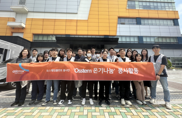 ▲오스템임플란트 사내 봉사 동호회 ‘OSSTEM 온기나눔’ 회원들이 4월 부산 수영천 플로깅 활동에 앞서 오스템임플란트 생산공장 건물(오렌지타워) 앞에서 기념촬영을 하고 있다. (사진제공=오스템임플란트)