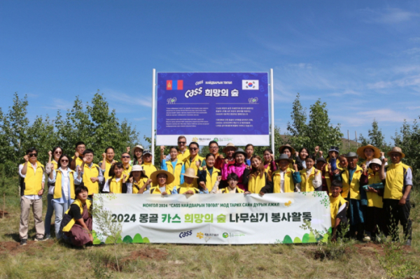 ▲24일 오비맥주 임직원들이 푸른아시아 관계자, 몽골 환경난민 등으로 구성된 봉사단과몽골 ‘카스 희망의 숲’ 기념 현판 앞에서 나무심기 봉사활동을 마치고 기념사진을 찍고 있다. (사진제공=오비맥주)