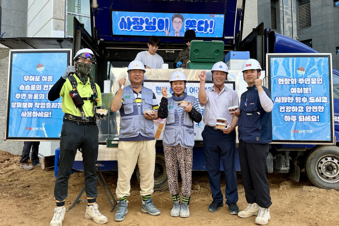 ▲삼환기업의 경기 파주시 운정동 경남아너스빌 건축현장 근로자들이 푸드트럭에서 팥빙수를 받은 뒤 사진 촬영을 하고 있다. (사진제공=SM그룹)