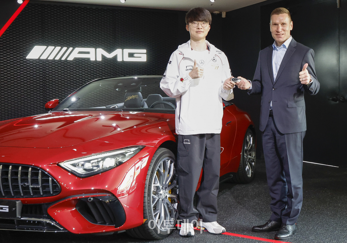 ▲T1 소속 '페이커' 이상혁(왼쪽)이 26일 서울 강남구 메르세데스-벤츠 AMG 전시장에서 맞춤 제작된 메르세데스-AMG SL 63 4MATIC+를 마티아스 바이틀 메르세데스-벤츠 코리아 대표이사에게 전달 받은 후 포즈를 취하고 있다. 인테리어 소재를 맞춤 제작하는 '마누팍투어' 프로그램이 적용된 이 차량에는 페이커 이상혁의 서명과 '전설의 전달(Hall of Legends)' 레터링이 머리 받침대, 바다 매트에 새겨져 있다. 조현호 기자 hyunho@