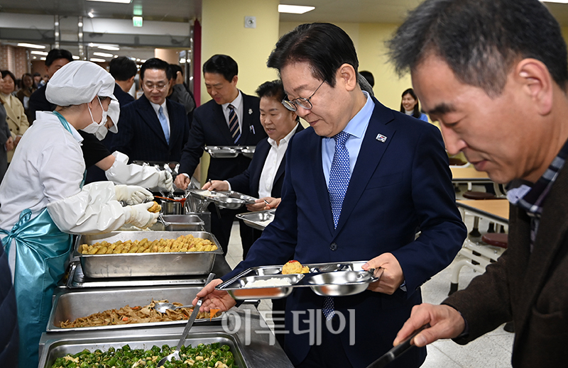 ▲2024년 11월 27일 당시 이재명 더불어민주당 대표가 서울 성동구 금호고에서 열린 고교 무상교육을 위한 현장 간담회를 마치고 식생활 교육실에서 배식을 받고 있다.  (국회사진취재단)