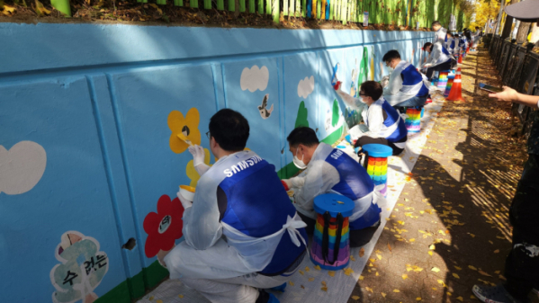 ▲삼성전자 임직원들이 12일 수원시 권선구 구운초등학교에서 벽화 그리기 봉사 활동에 참여하고 있다. (자료제공=삼성)