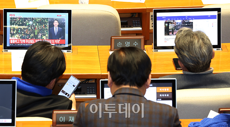 ▲더불어민주당 의원들이 7일 서울 여의도 국회에서 열린 본회의에서 국민의힘 의원들이 윤석열 대통령 탄핵소추안 투표를 거부하고 퇴장하자 회의장에서 뉴스를 보며 대기하고 있다. 고이란 기자 photoeran@