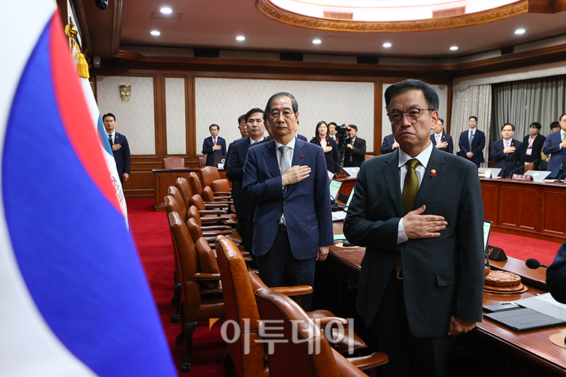 ▲한덕수 대통령 권한대행 국무총리가 19일 서울 종로구 정부서울청사에서 열린 임시국무회의에서 국민의례를 하고 있다. 오른쪽은 최상목 경제부총리 겸 기획재정부 장관. 사진제공 총리실