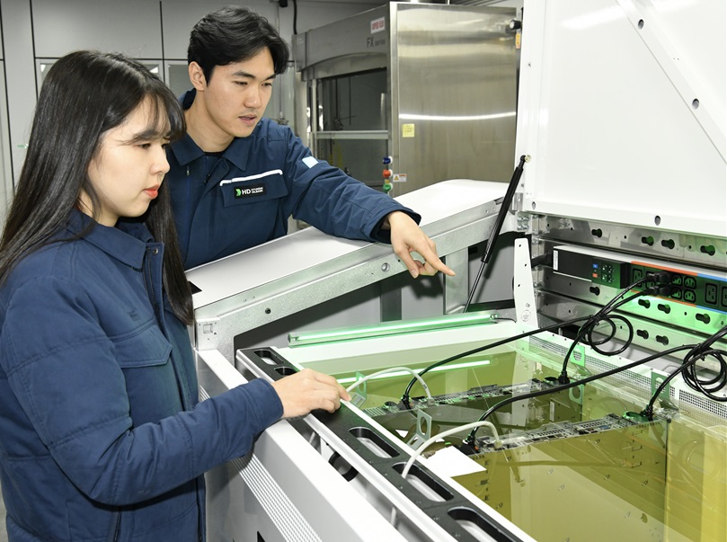 ▲액침냉각설비에 담긴 냉각유와 서버를 테스트하고 있는 HD현대오일뱅크 직원들 (자료제공=HD현대오일뱅크)