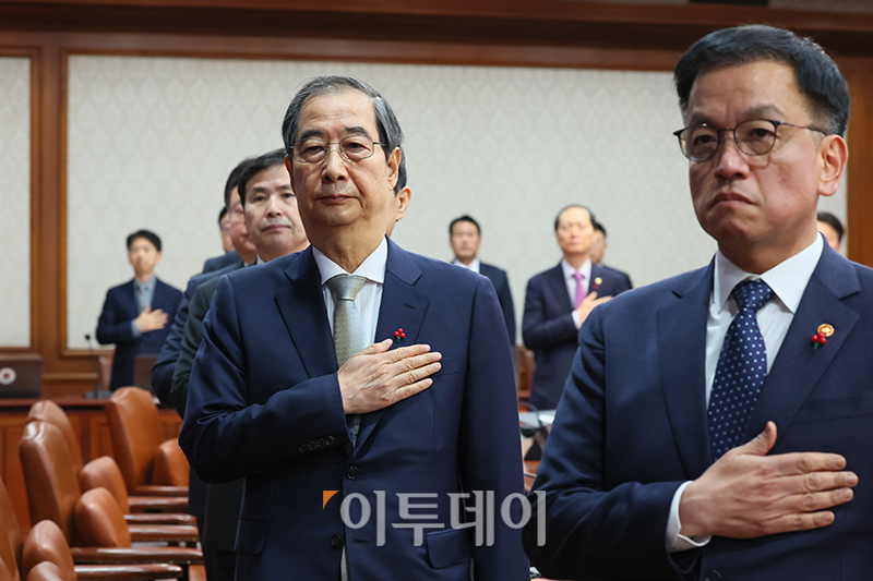 ▲한덕수 대통령 권한대행 국무총리가 24일 서울 종로구 정부서울청사에서 열린 국무회의에서 국민의례를 하고 있다. 오른쪽은 최상목 경제부총리 겸 기획재정부 장관. 사진제공 총리실