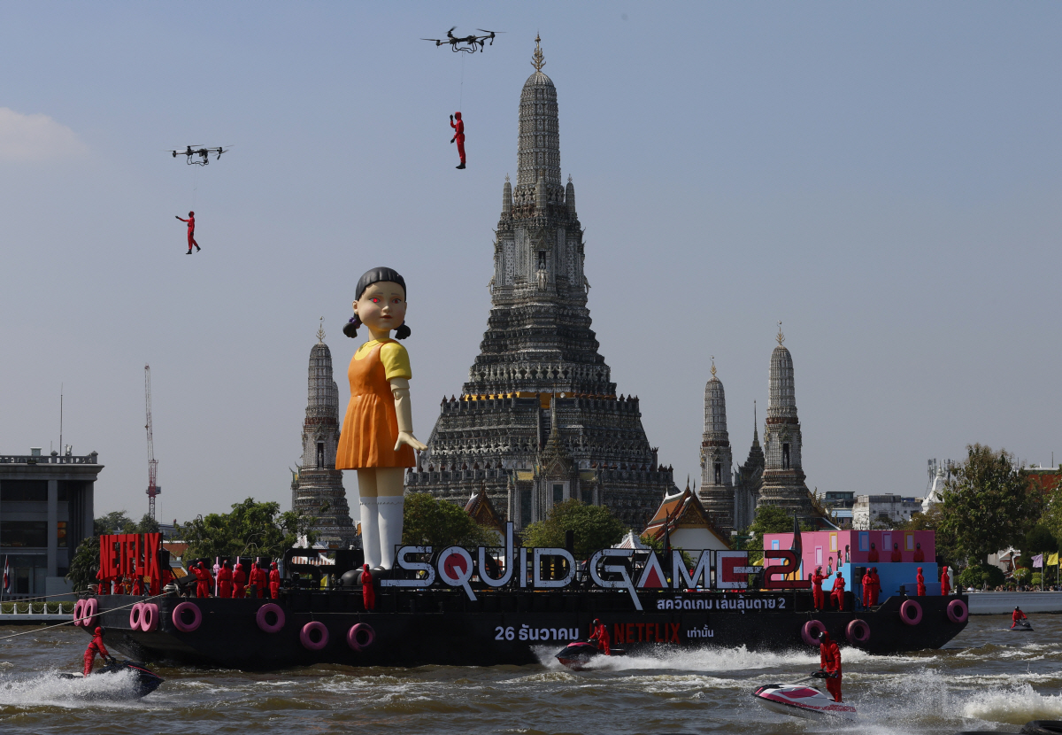 ▲태국 방콕의 짜오프라야 강에서 지난달 21일(현지시간) 오징어게임 시즌2를 홍보하기 위한 대형 ‘영희’ 인형이 왓 아룬 사원 앞을 지나가고 있다. 방콕/EPA연합뉴스