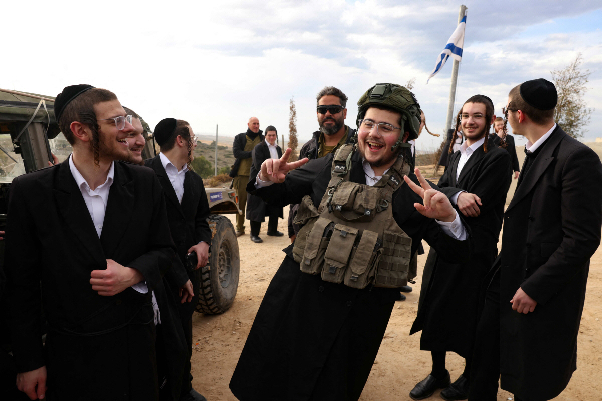 ▲이스라엘 스데롯에서 5일(현지시간) 초정통파 유대교도가 방탄모와 탄창 조끼를 착용한 채 웃고 있다. 스데롯(이스라엘)/AFP연합뉴스