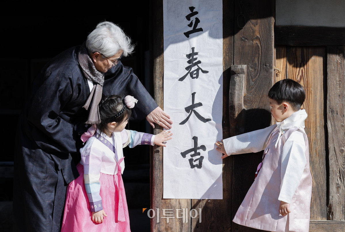 ▲절기상 봄이 시작된다는 입춘인 3일 서울 종로구 국립민속박물관 오촌댁에서 열린 입춘 세시행사에서 송현수 서예가와 아이들이 대문에 '입춘대길'이라고 쓴 입춘첩을 붙이고 있다. 조현호 기자 hyunho@