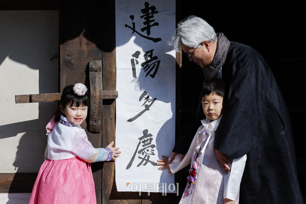 ▲절기상 봄이 시작된다는 입춘인 3일 서울 종로구 국립민속박물관 오촌댁에서 열린 입춘 세시행사에서 송현수 서예가와 아이들이 대문에 '건양다경'이라고 쓴 입춘첩을 붙이고 있다. 조현호 기자 hyunho@