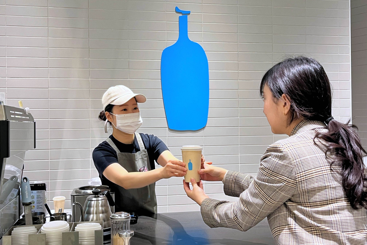 ▲4일 한 여성고객이 타임빌라스 수원 3층 다이닝 에비뉴에서 진행 중인 ‘블루보틀’ 팝업스토어에서 음료를 받고 있다. (사진제공=롯데백화점)