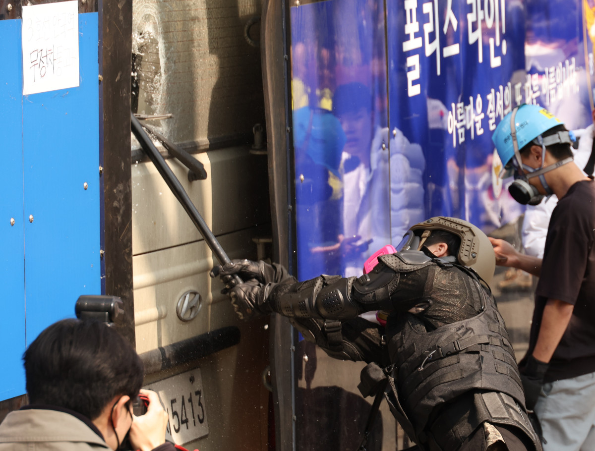 ▲4일 서울 종로구 헌법재판소 인근에서 윤석열 대통령 지지 집회 참가자 중 한 명이 헌재의 윤 대통령 파면 결정에 경찰이 세운 가벽 사이로 보이는 차량을 부수고 있다. (연합뉴스)
