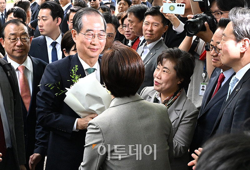 ▲한덕수 무소속 대선 예비후보가 8일 김문수 국민의힘 후보와 단일화 관련 회동을 위해 서울 국회 사랑재에 위치한 커피숍으로 향하는 길에서 꽃다발을 받고 있다. 고이란 기자 photoeran@