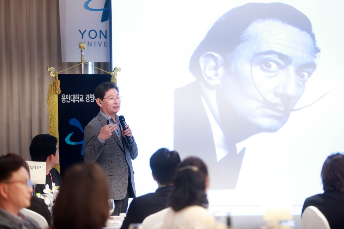 ▲이상일 용인특례시장이 용인대학교 경영대학원 최고경영자과정에서 특강을 진행하며 연단에서 발표를 하고 있고, 배경에는 살바도르 달리의 초상이 보인다.
