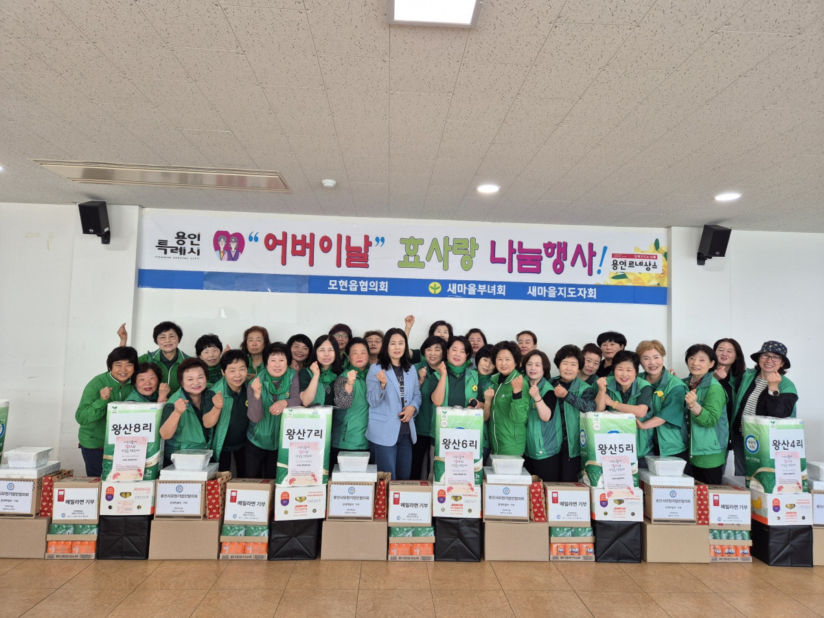 ▲용인특례시의 모현읍협의회가 주최한 어버이날 효사랑 나눔 행사에서 여러 명의 사람들이 초록색 조끼를 입고 기념 촬영을 하고 있으며, 앞에는 어버이날 기념 기부물품이 놓여 있다. (용인특례시)
