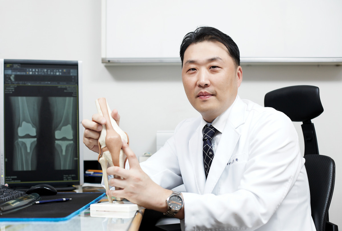 ▲윤성환 장산의료재단 수원 이춘택병원장이 무릎 모형을 들고 모니터에 보이는 무릎의 엑스레이 사진을 통해 무릎 퇴행성 관절염 진료에 대해 설명하고 있다. (이춘택병원)
