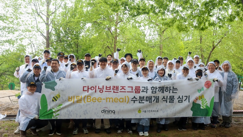 ▲9일 서울 광진구 서울어린이대공원 플랜비가든에서 다이닝브랜즈그룹 임직원들이 수분 매개 식물 심기 캠페인 기념 단체 사진을 촬영하고 있다. (사진제공=다이닝브랜즈그룹)