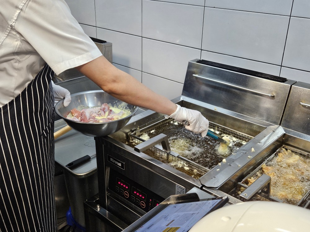 ▲교촌199스쿨 시연자가 치킨 조각을 기름에 넣어 튀기고 있다.  (사진=문현호 기자 m2h@)