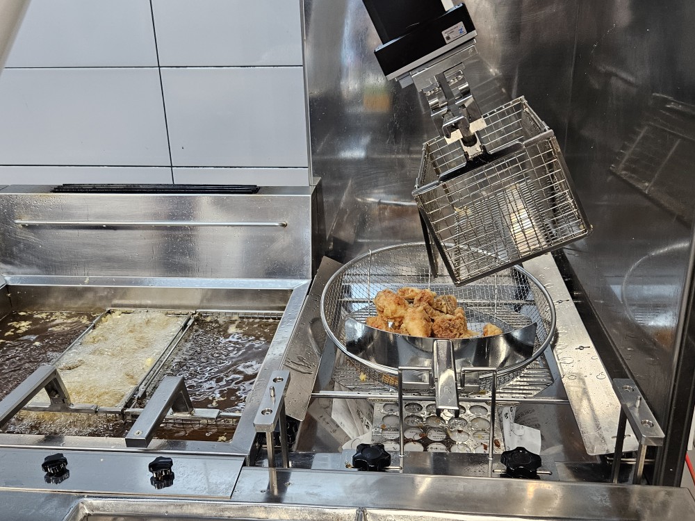 ▲조리 로봇이 치킨의 기름을 털어내는 작업을 마친 뒤 뜰채에 담고 있다. (사진=문현호 기자 m2h@)