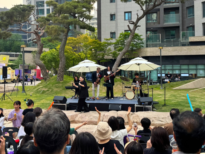 ▲디에이치 자이 개포 단지 내 중앙광장에서 열린 '잔디밭 뮤직 페스티벌'에서 입주민들이 가수 난아진과 쿨재즈밴드의 공연을 즐기고 있다. (사진제공=현대건설)