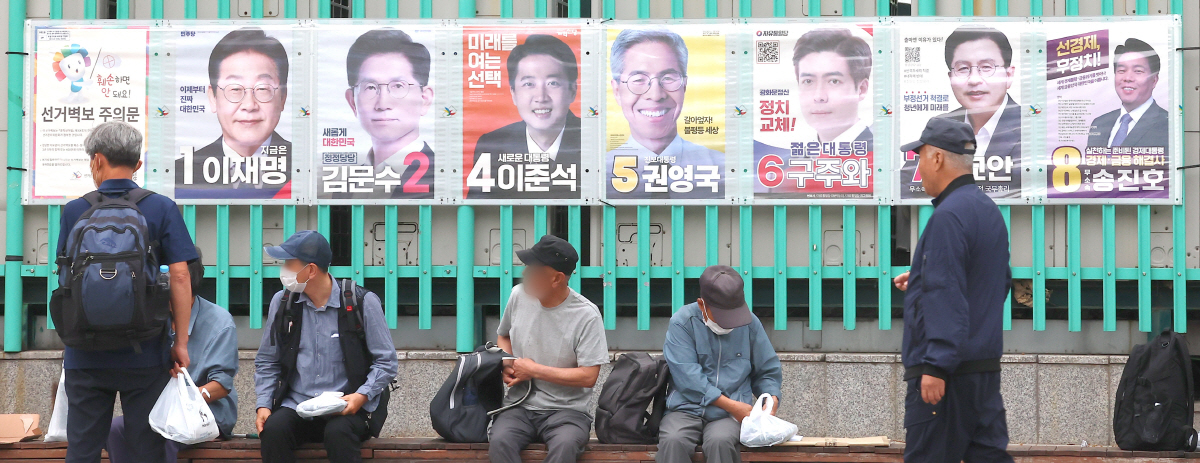 ▲제21대 대통령선거를 하루 앞둔 2일 인천 부평구 부평역 광장에 게시된 선거 후보 벽보 아래에서 노인들이 도시락 무료 급식을 받고 있다. 연합뉴스