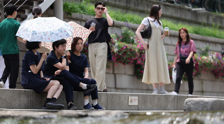▲지난달 26일 서울 중구 청계천에서 양산을 쓴 시민들이 휴식을 취하고 있다. (뉴시스)