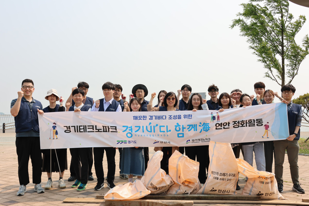 ▲경기테크노파크 임직원 20여명이 안산시 시화MTV 인근 호안에서 연안 정화활동을 실시하고 수거한 쓰레기 자루 앞에서 단체사진을 촬영하고 있다. (경기테크노파크)