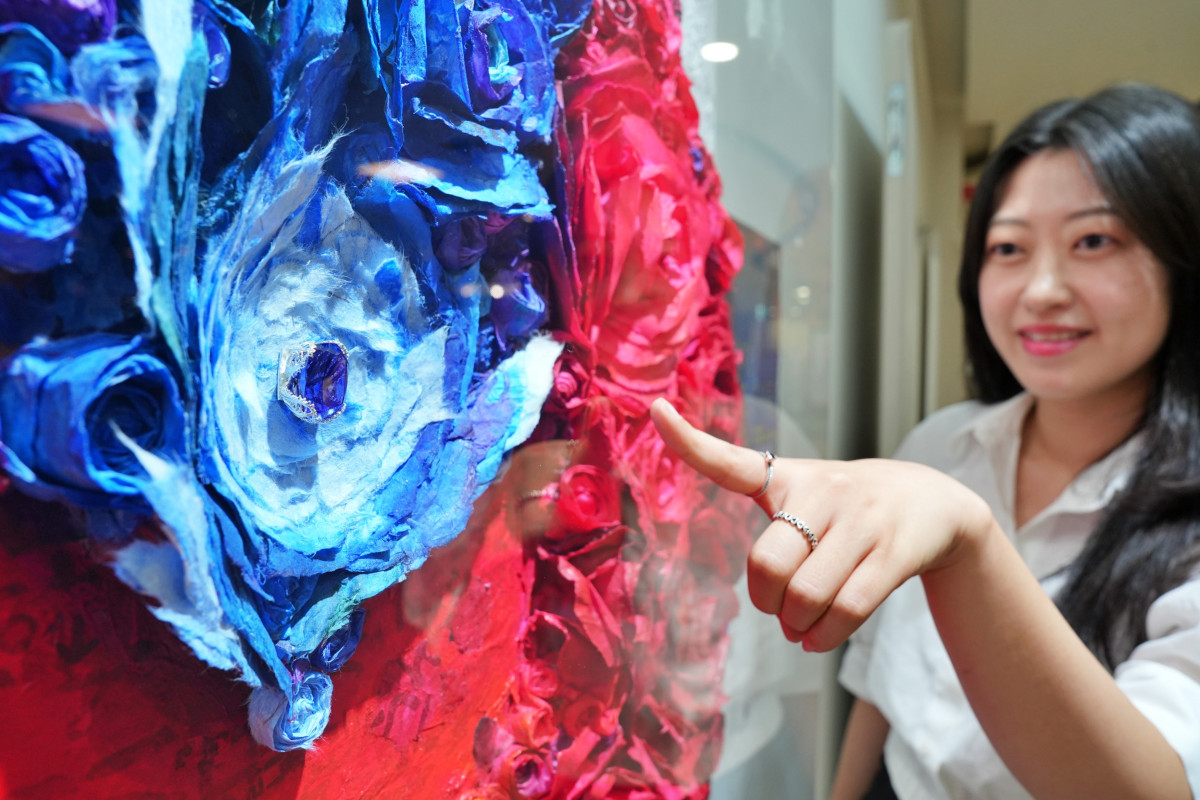 ▲서울시 송파구에 위치한 롯데마트 송파점 엠아트센터에서 로즈박 작가의 '한지 아프리카를 품다(불멸과 사랑)' 작품 내 탄자나이트를 보는 전유라 MD의 모습 (사진제공=롯데마트)