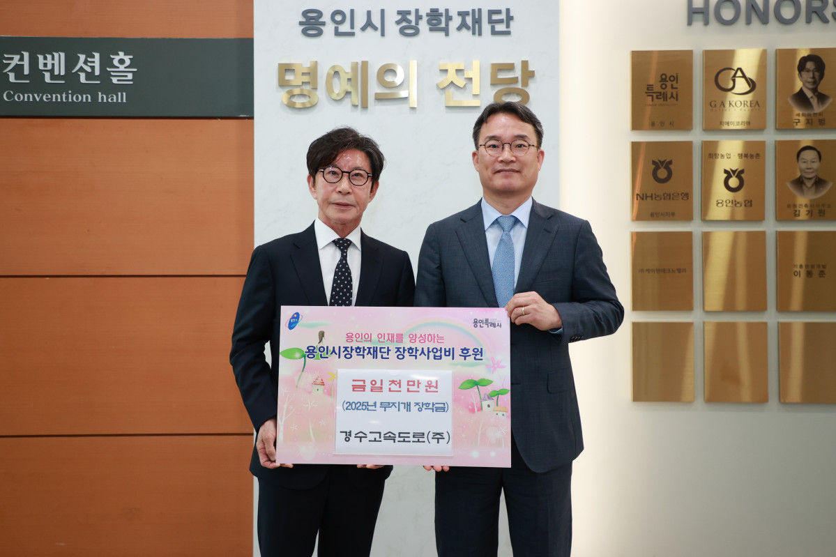 ▲김재성 경수고속도로 대표이사가 용인시 장학재단 행사에서 구자범 이사장과 함께 2025년 무지개 장학금 1000만 원 기부를 나타내는 보드판을 들고 명예의 전당 앞에 서 있다. (용인시 장학재단)