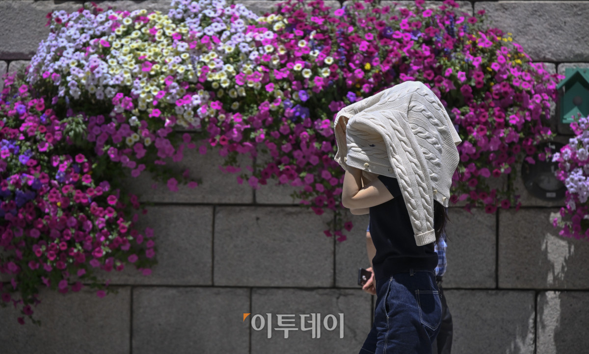 ▲서울의 한낮 기온이 32도를 기록하는 등 올해 들어 가장 더운 날씨를 보인 12일 서울 중구 청계천 일대에서 한 시민이 겉옷으로 더위를 피하며 발걸음을 옮기고 있다. 조현호 기자 hyunho@