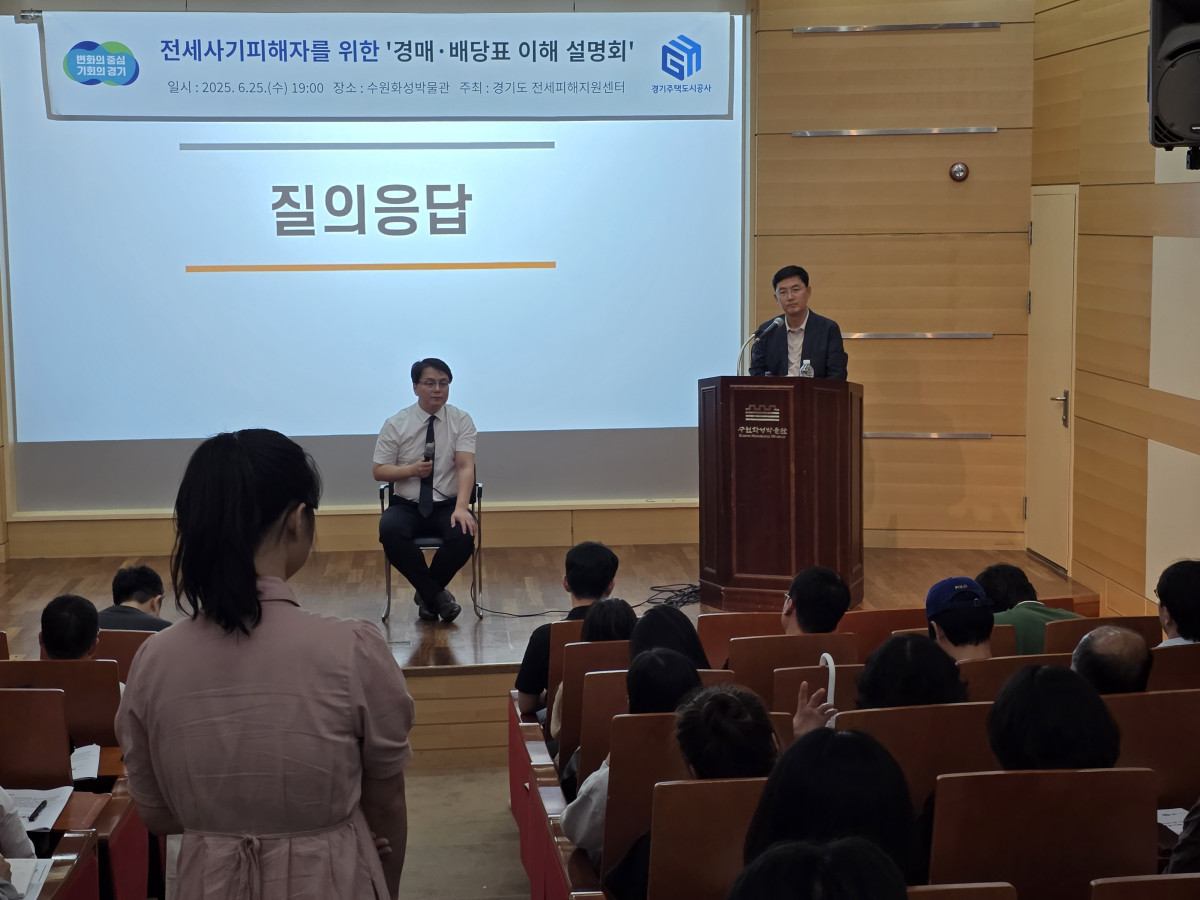 ▲경기도 주거복지센터의 전세사기 피해자 대상 설명회에서 한 참석자가 질의응답 시간에 질문하고, 두 명의 발표자가 무대에서 답변하고 있다. (경기주택도시공사(GH))