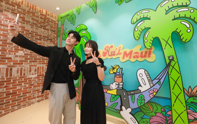 ▲29일 오전 현대백화점 판교점에서 고객들이 글로벌 팝 아티스트 작가 스티븐 해링턴의 하와이 콘셉트 그래픽 앞에서 기념사진을 찍고 있다.   (사진제공=현대백화점그룹)