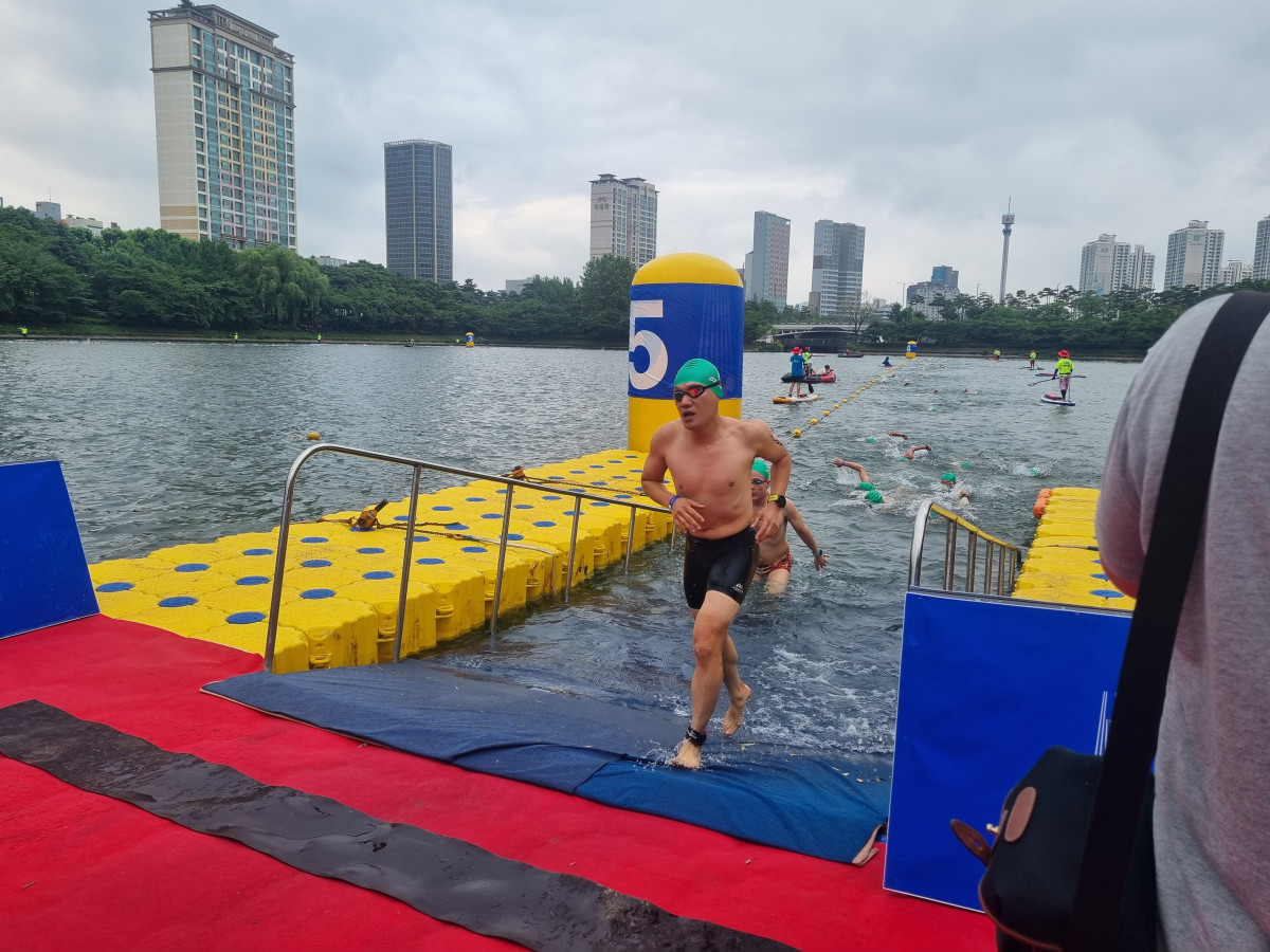 ▲이날 오전 7시 8분께 참가자들이 석촌호수를 한 바퀴 수영한 뒤 두 번째 바퀴를 돌기 위해 올라오고 있다.  (유하영 기자 haha@)