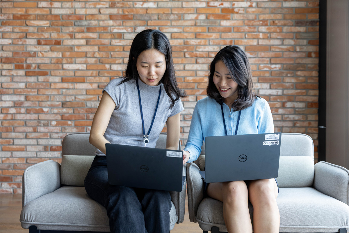 ▲금융 분야 인재 개발 프로그램(CFDP)을 통해 쿠팡에 입사한 구현지 씨(사진 왼쪽)와 조한나 씨가 사내 라운지에서 노트북을 보며 업무에 대해 의견을 나누고 있다. (사진제공=쿠팡)
