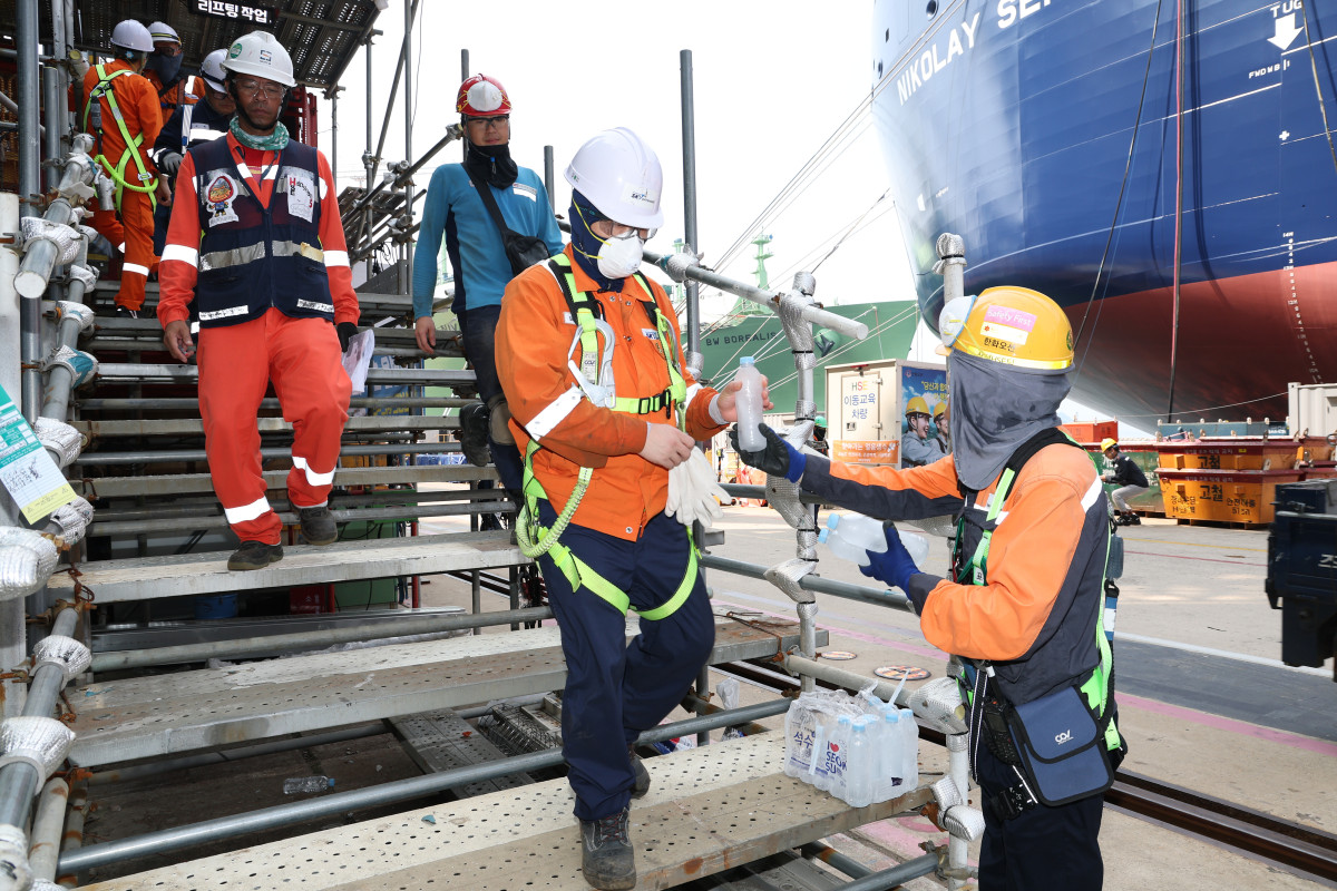 ▲한화오션 안전관리자가 오후 쉬는 시간 휴식을 위해 하선하는 작업자들에게 얼음 생수를 전달하고 있다. (사진제공=한화오션)