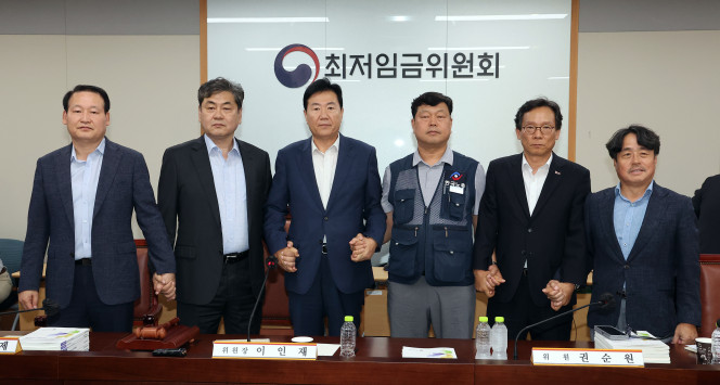 ▲10일 정부세종청사에서 열린 제12차 전원회의에서 내년 최저임금을 시간당 1만320원으로 17년만에 합의로 결정한 공익위원-사용자위원-근로자위원들이 손을 잡고 기념촬영을 하고 있다. 왼쪽부터 하헌제 상임위원, 이인재 위원장, 사용자위원인 류기정 한국경영자총협회 전무, 근로자위원인 류기섭 한국노총 사무총장, 사용자위원인 이명로 중소기업중앙회 인력정책본부장, 공익위원인 권순원 숙명여대 교수. 2025.7.11 (연합뉴스)