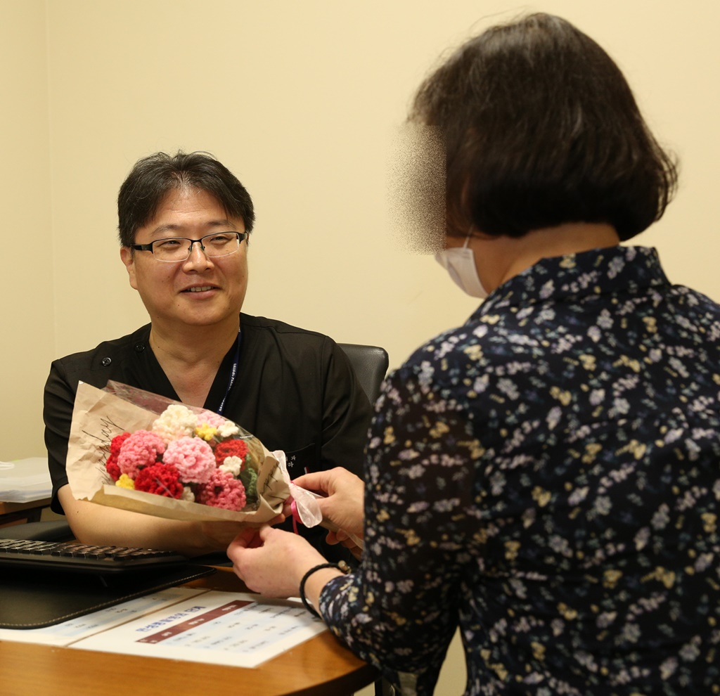▲두 번째 신장이식 수술로 건강을 되찾은 50대 여성 경 모 씨가 정병하 서울성모병원 신장내과 교수에게 뜨개질로 만든 카네이션 꽃다발을 전하고 있다.    (서울성모병원)