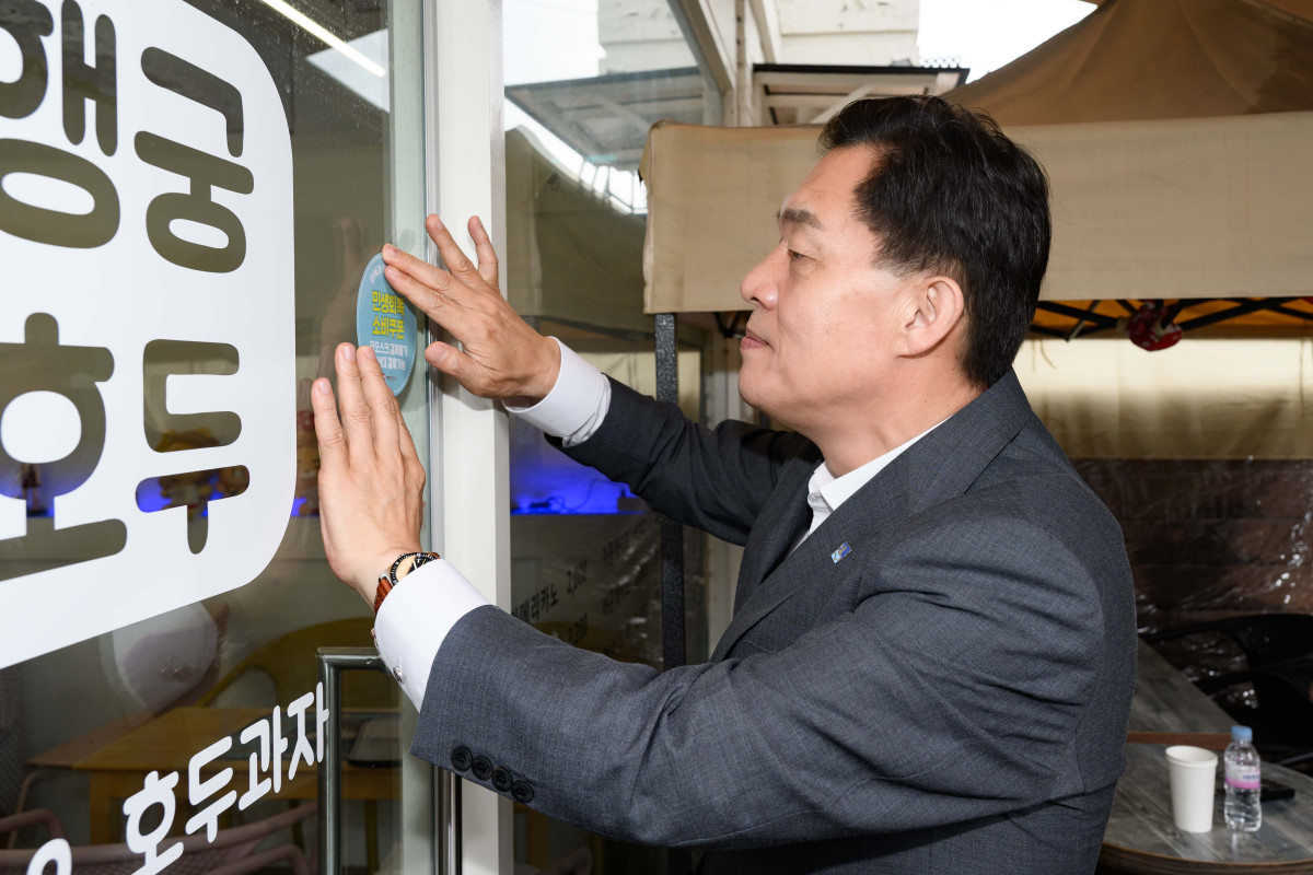 ▲이재준 수원시장이 행궁동에 한 민생회복소비쿠폰 사용처에 스티커를 부착하고 있다. (수원특례시)