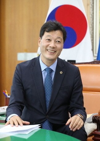 ▲전남도의 개발이익 환수 문제를 지적한 392회 임시회가 열린 가운데, 정장 차림의 인물이 태극기와 서류가 놓인 책상 앞 실내에서 촬영된 모습이 보인다. (사진제공=전남도의회)
