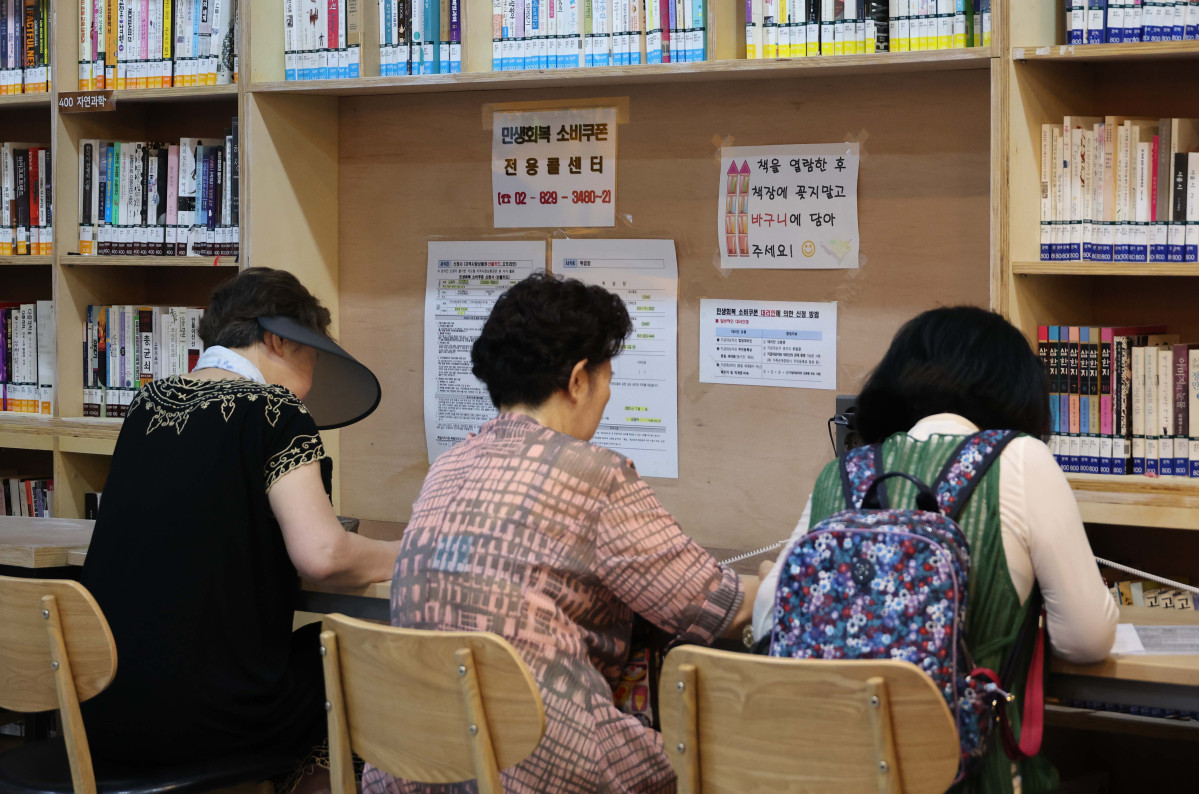 ▲민생회복 소비쿠폰 신청이 시작된 21일 서울 동작구 대방동주민센터 작은도서관에서 시민들이 소비쿠폰 신청서를 작성하고 있다. 신태현 기자 holjjak@