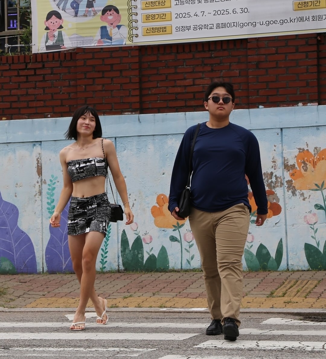 ▲의정부고 졸업사진 현장, 지난해 7월 미국 LA 베벌리힐스 거리에서 함께 걷는 모습이 포착돼 화제를 모았던 방시혁 하이브 의장과 BJ 과즙세연을 표현하고 있다. (출처=의정부고 학생자치회 인스타그램 캡처)