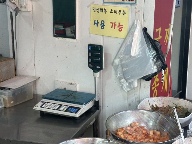 ▲22일 오전 서울 관악구 관악중부시장 내 한 반찬가게에 ‘민생회복 소비쿠폰 사용 가능’ 안내판이 붙어있다. (서이원 기자 iwonseo96@)