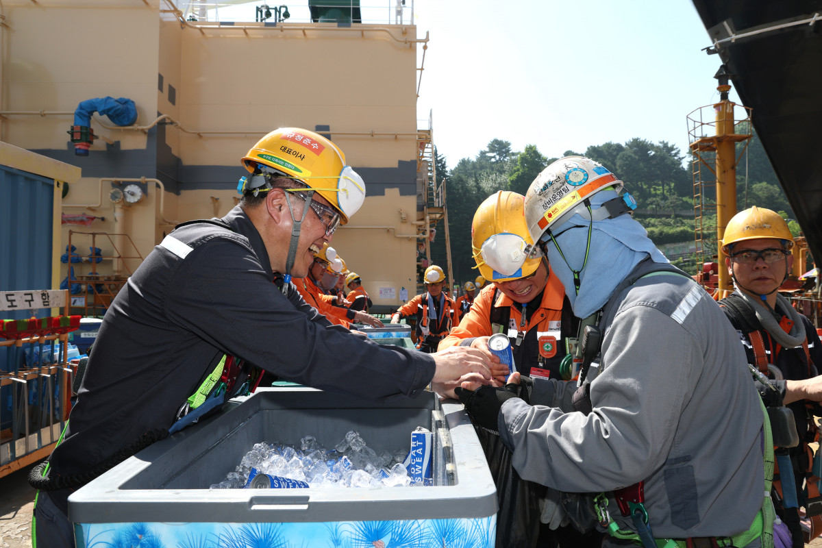 ▲한화오션 김희철 대표이사(왼쪽)가 거제사업장 1도크 주변에서 근로자들에게 시원한 음료를 건네주고 있다. (사진= 한화오션)