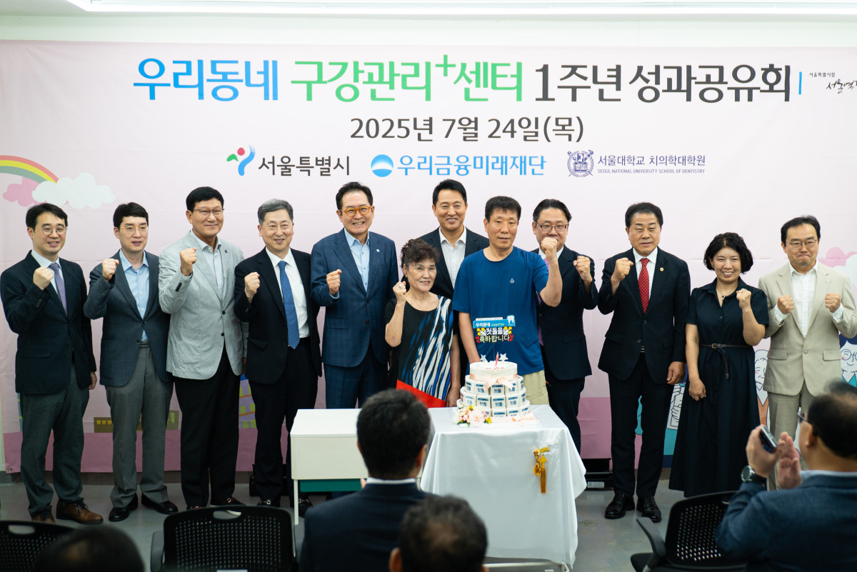 ▲24일 우리동네 구강관리플러스센터에서 오세훈 서울시장(가운데), 장광익 우리금융미래재단 사무국장(왼쪽에서 다섯번째)이 쪽방촌 주민들과 함께 1주년 기념떡을 컷팅하고 있다. (사진=우리금융미래재단)