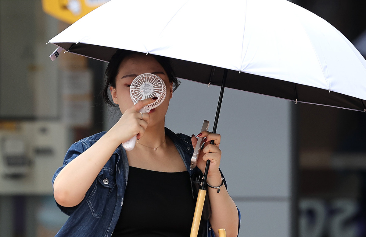 ▲23일 대구 중구 동성로에서 한 시민이 우산과 손 선풍기를 들고 길을 걷고 있다. (뉴시스)
