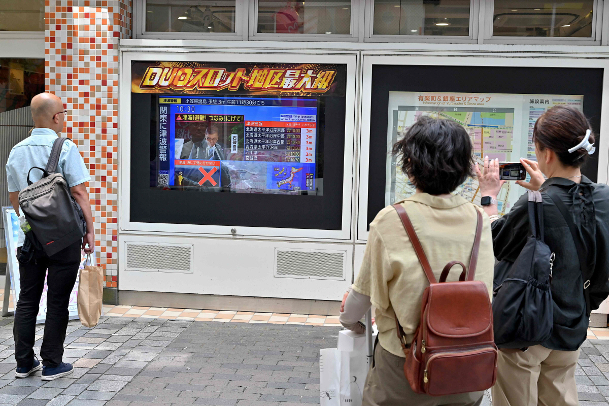 ▲30일(현지시간) 일본 도쿄에서 사람들이 쓰나미 경보와 관련한 TV 방송을 보고 있다. 도쿄/AFP연합뉴스